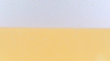 Yüzeydeki köpükte bir bardak hafif bira ve hava kabarcıkları.