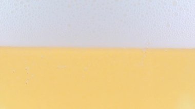 Yüzeydeki köpükte bir bardak hafif bira ve hava kabarcıkları.