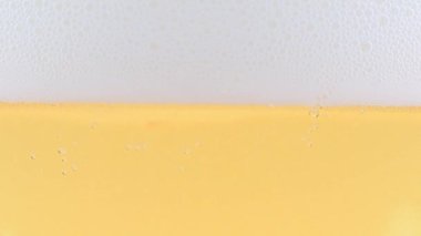 Yüzeydeki köpükte bir bardak hafif bira ve hava kabarcıkları.