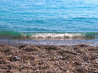 Güzel deniz dalgaları çakıl taşı sahilinde yuvarlanıyor.