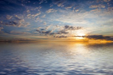 Sakin deniz suyu yüzeyindeki bulutlu gökyüzünün hoş yansıması