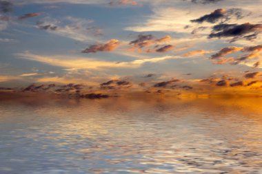 Sakin deniz suyu yüzeyindeki bulutlu gökyüzünün hoş yansıması