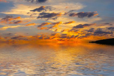 Sakin deniz suyu yüzeyindeki bulutlu gökyüzünün hoş yansıması