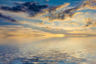 Sakin deniz suyu yüzeyindeki bulutlu gökyüzünün hoş yansıması