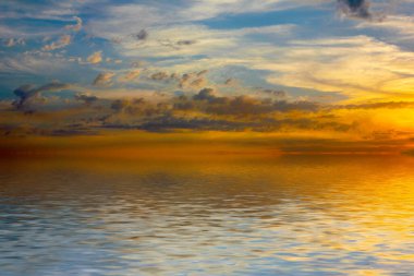 Sakin deniz suyu yüzeyindeki bulutlu gökyüzünün hoş yansıması