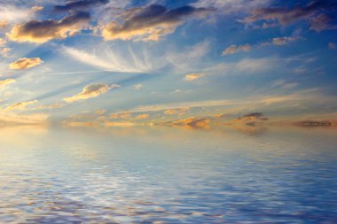 Sakin deniz suyu yüzeyindeki bulutlu gökyüzünün hoş yansıması