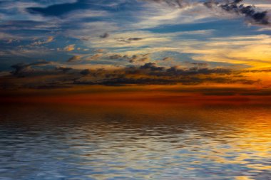 Sakin deniz suyu yüzeyindeki bulutlu gökyüzünün hoş yansıması