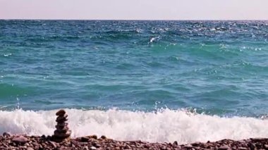 Aktif eğlence için güzel dalgalar ve çakıl taşlı deniz plajı