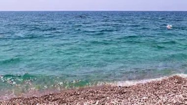 Aktif eğlence için güzel dalgalar ve çakıl taşlı deniz plajı