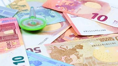Finansal piyasanın sürdürülebilirliğinin bir sembolü olarak çocuk plastik oyuncağının kağıt para yığınının üzerinde dönmesi.