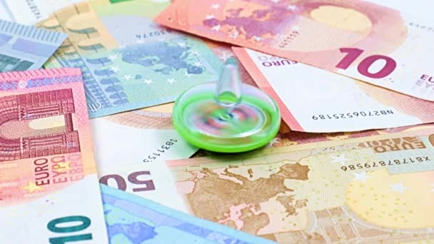 金融市場の持続可能性の象徴として紙のユーロの山の上で子供のプラスチック製のおもちゃの旋回の回転 — ストック動画