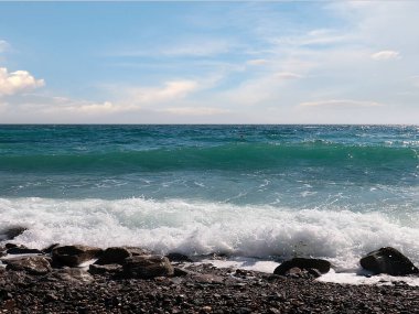 Güzel çakıl taşı plajı ve tatil köyündeki bulutlu gökyüzü.