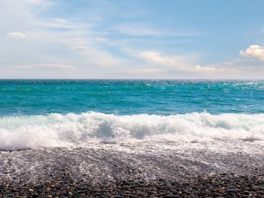 Güzel çakıl taşı plajı ve tatil köyündeki bulutlu gökyüzü.