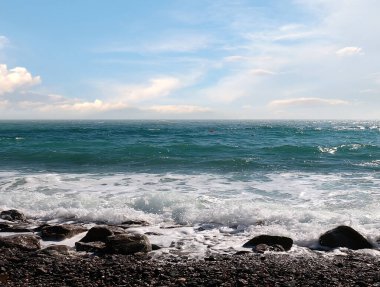 Güzel çakıl taşı plajı ve tatil köyündeki bulutlu gökyüzü.
