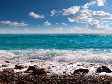 Güzel çakıl taşı plajı ve tatil köyündeki bulutlu gökyüzü.