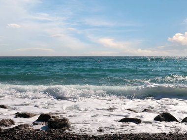 Güzel çakıl taşı plajı ve tatil köyündeki bulutlu gökyüzü.