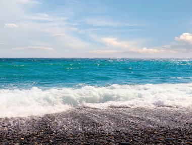 Güzel çakıl taşı plajı ve tatil köyündeki bulutlu gökyüzü.