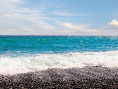 Güzel çakıl taşı plajı ve tatil köyündeki bulutlu gökyüzü.