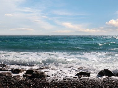 Güzel çakıl taşı plajı ve tatil köyündeki bulutlu gökyüzü.