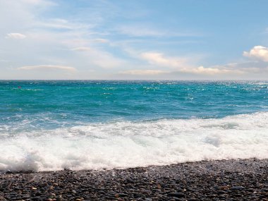 Güzel çakıl taşı plajı ve tatil köyündeki bulutlu gökyüzü.