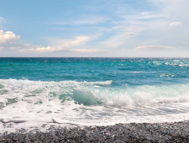 Çakıl taşı plajı ve güneşli gökyüzü olan güzel deniz manzarası.