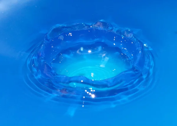 落下するときに純粋な透明な水の滴が液体のパターンを作り出します — ストック写真