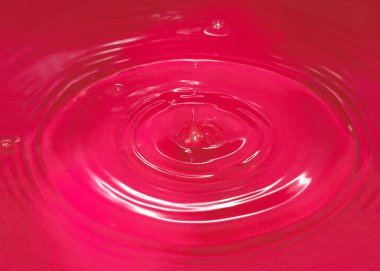 Bir damla kan kırmızı sıvı suyun yüzeyine düşer.