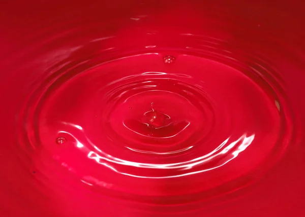 一滴血红色的液体落在水面上 — 图库照片