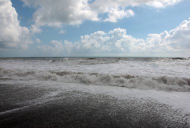 Güzel fırtına dalgaları ve bulutlu gökyüzünün altında deniz plajı