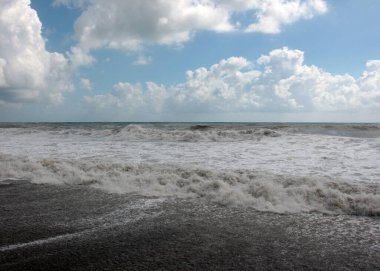 Güzel fırtına dalgaları ve bulutlu gökyüzünün altında deniz plajı