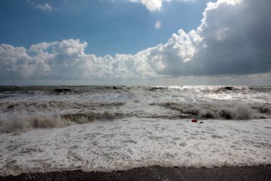 Güzel fırtına dalgaları ve bulutlu gökyüzünün altında deniz plajı
