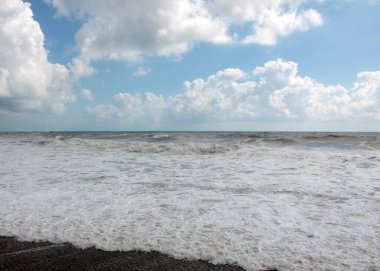 Güzel fırtına dalgaları ve bulutlu gökyüzünün altında deniz plajı