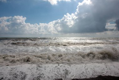 Güzel fırtına dalgaları ve bulutlu gökyüzünün altında deniz plajı