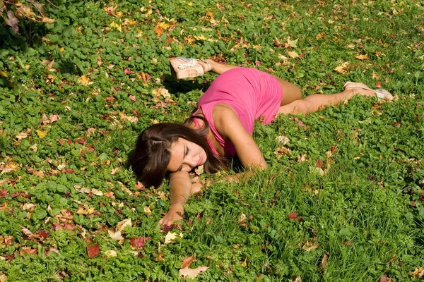 Sonbahar Park çimlerin üzerine oturan kız — Stok fotoğraf