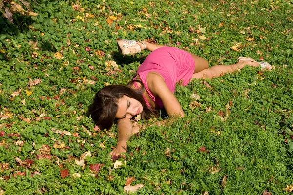 Meisje rusten op gras in herfst park Stockfoto