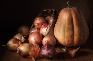 Koyu ahşap arka planda soğan ve balkabağı.