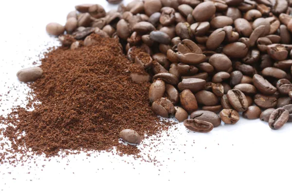 Whole and ground coffee beans scattered on white background — Stock Photo, Image