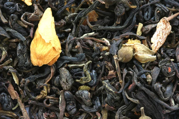 Droge zwarte thee op smaak gebracht met droge bloemknoppen achtergrond — Stockfoto