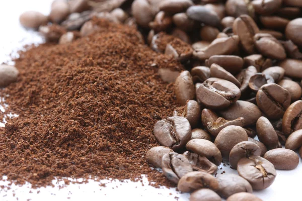 Whole and ground coffee beans scattered on white background Royalty Free Stock Photos