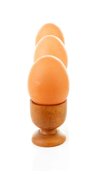Three chicken eggs in wooden holder — Stock Photo, Image