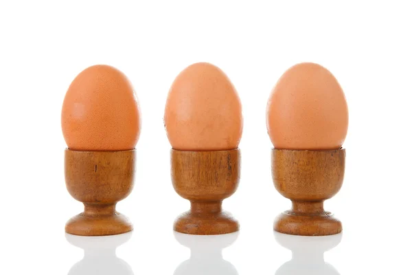 Trzy jaja kurze w drewnianym uchwytem — Zdjęcie stockowe