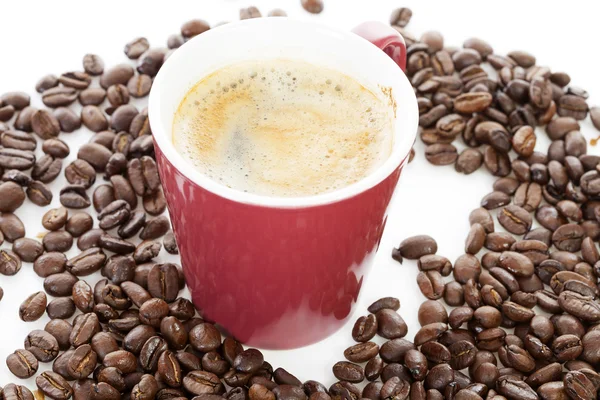 Kaffekopp i högen av rostade bönor — Stockfoto