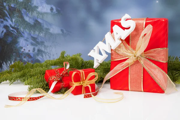 Het woord xmas opknoping over rode Kerst presenteert — Stockfoto