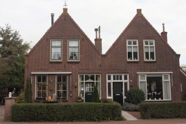 Güzel küçük bir ev, kırmızı tuğladan yapılmış, arkasında mavi gökyüzü.