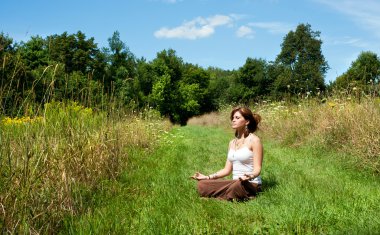 Genç kadın doğada meditasyon yapıyor.