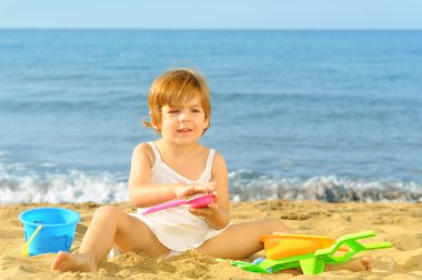 Kumsalda onun oyuncakları ile oynarken mutlu bebek kız