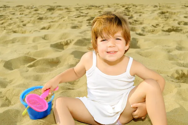 Happy toddler girl playing with her toys at beach — Stock Photo, Image