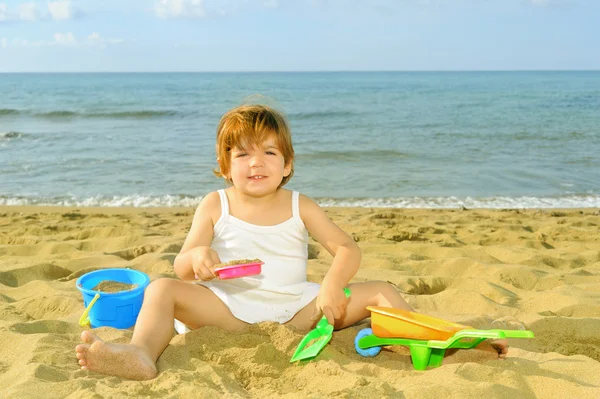 Glada barnet Tjej leker med hennes leksaker på stranden — Stockfoto