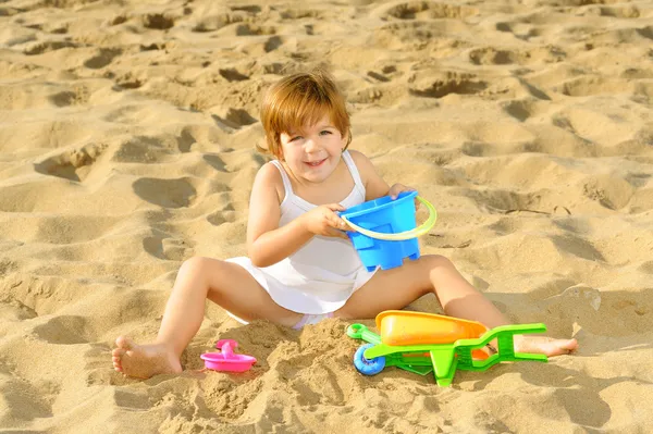 Feliz niña jugando con sus juguetes en la playa —  Fotos de Stock