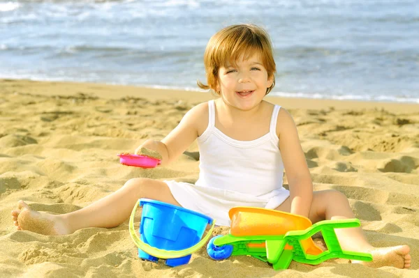 Happy toddler girl playing with her toys at beach — Stock Photo, Image